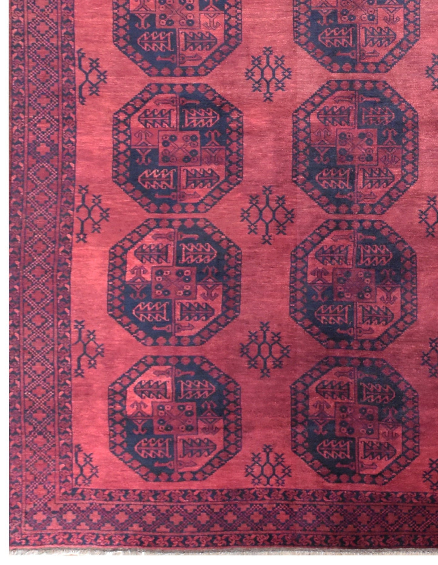 A vintage Afghan Turkmen rug featuring repeating dark octagonal motifs on a deep red wool field.
