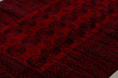 A vintage handmade Afghan Turkmen rug featuring a deep red field with repeating geometric motifs.