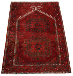 A vintage handmade Afghan Turkmen wool rug featuring two dark geometric medallions on a red field.