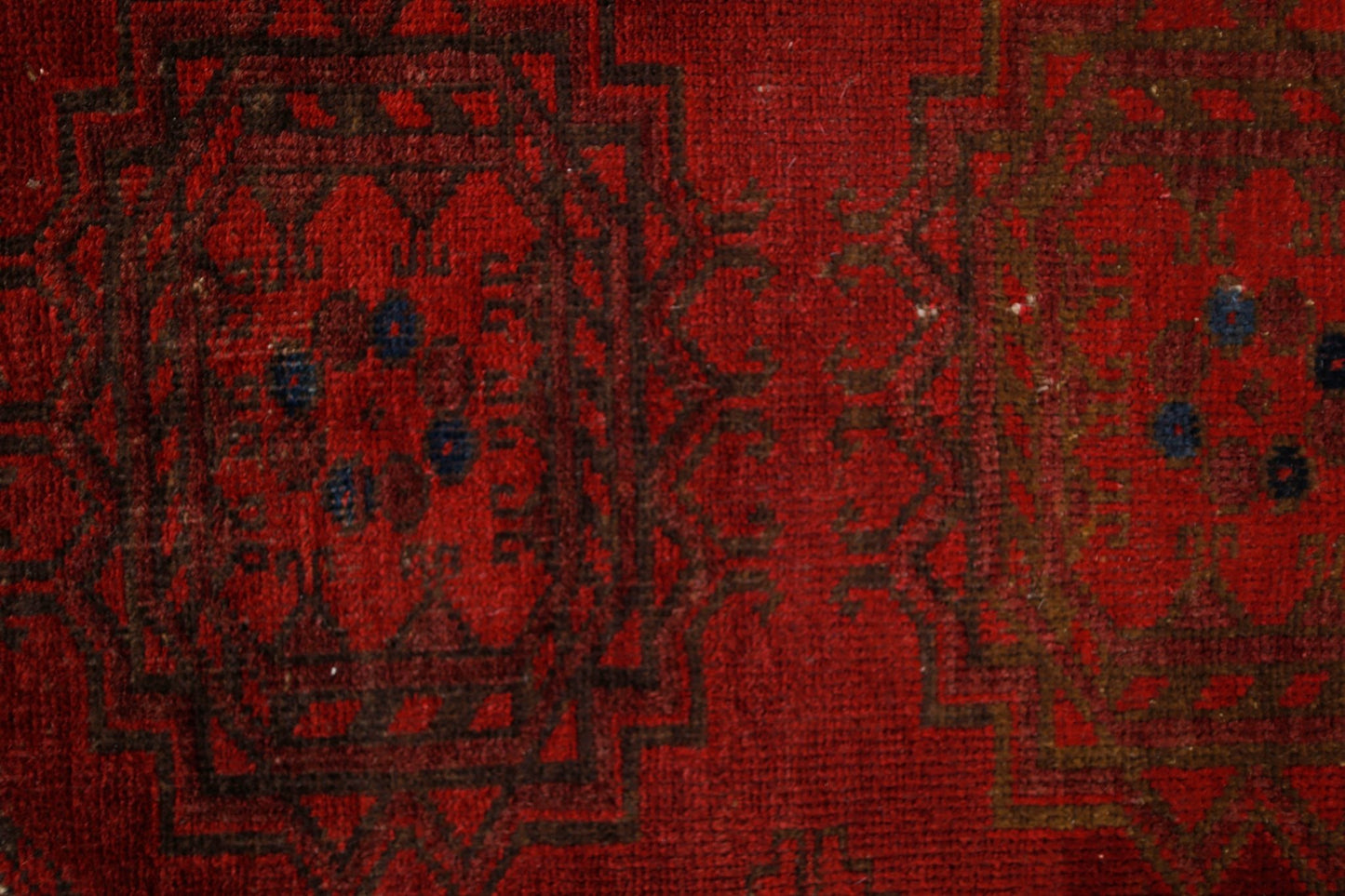 A vintage handmade Afghan Turkmen rug featuring traditional geometric patterns in deep red wool.
