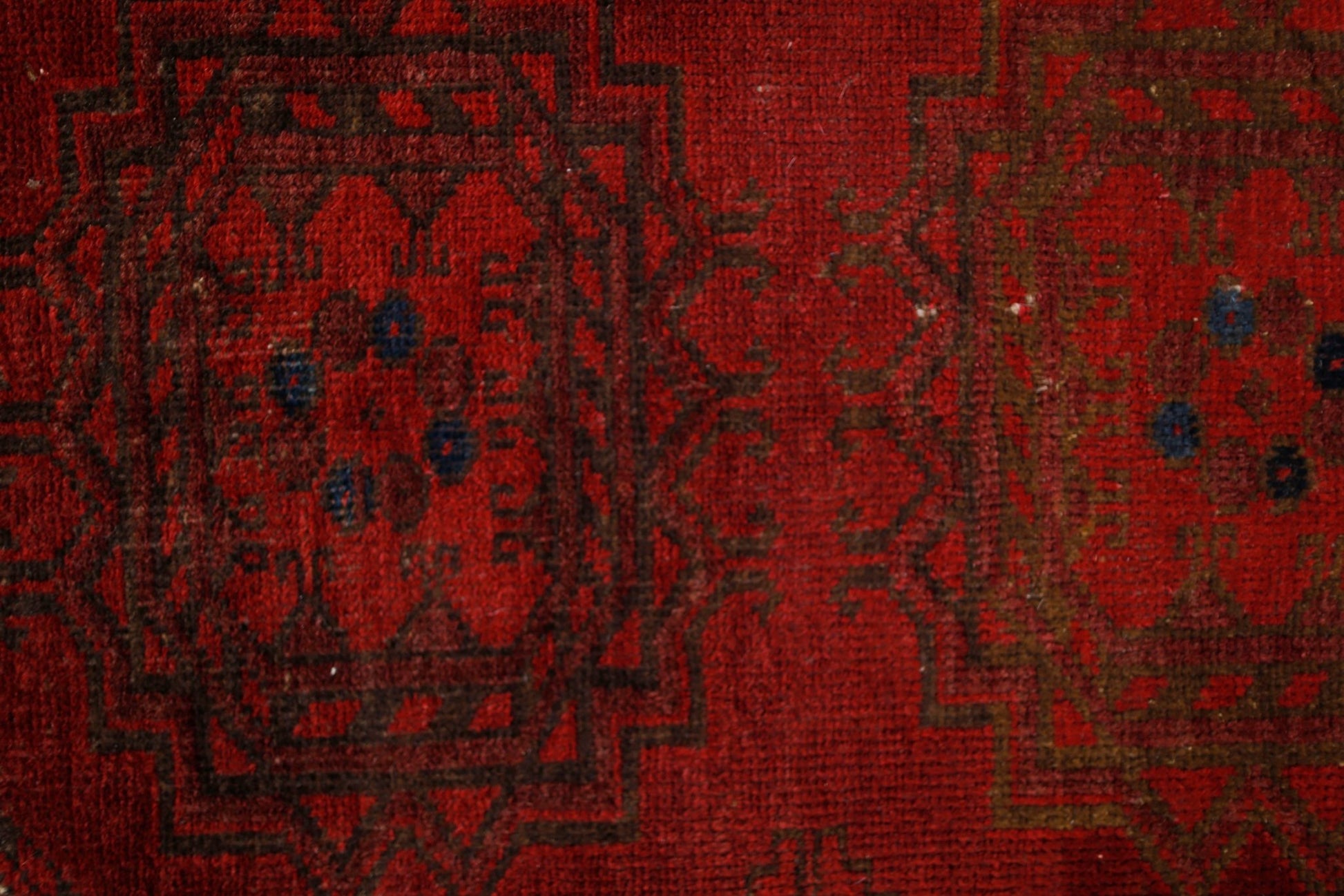 A vintage handmade Afghan Turkmen rug featuring traditional geometric patterns in deep red wool.