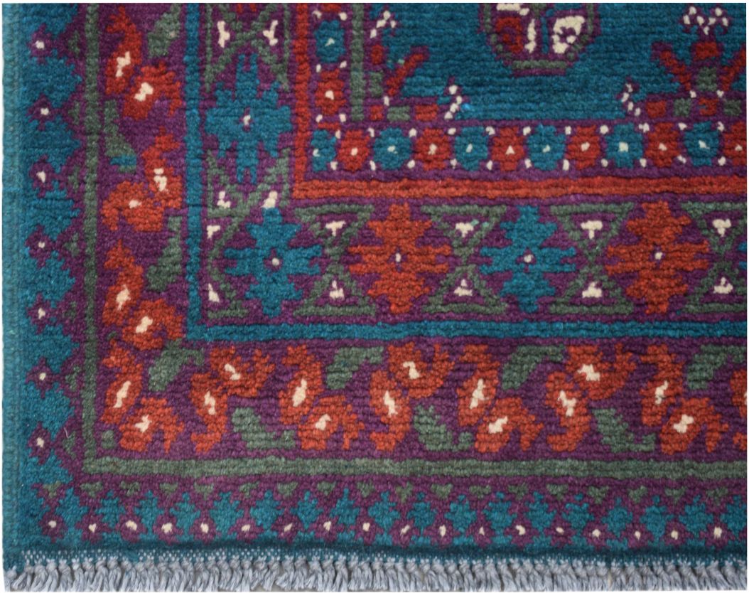 A vintage Afghan Turkmen runner featuring geometric patterns in teal, purple, and red wool.