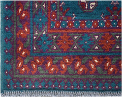 A vintage Afghan Turkmen runner featuring geometric patterns in teal, purple, and red wool.