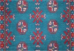 A vintage Afghan Turkmen runner featuring a teal background with repeating red and purple motifs.