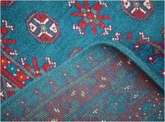 A vintage Afghan Turkmen runner featuring geometric patterns in red, purple, and teal wool.
