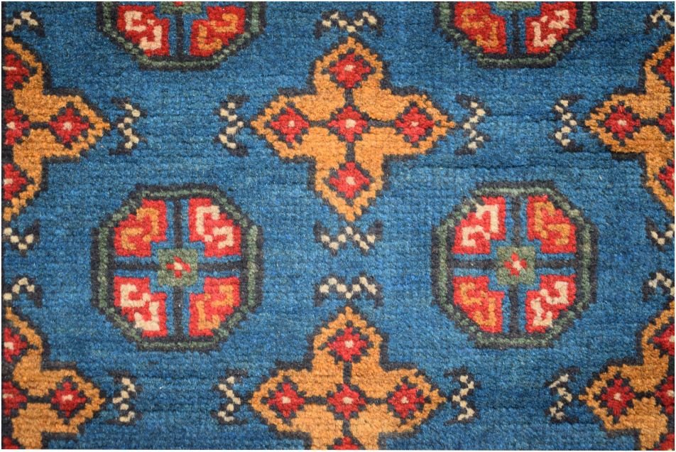 A vintage Afghan Turkmen runner featuring a geometric pattern of red and gold motifs on a blue field.