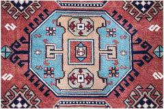 A vintage handwoven Caucasian rug featuring a geometric medallion pattern in red, blue, and tan.