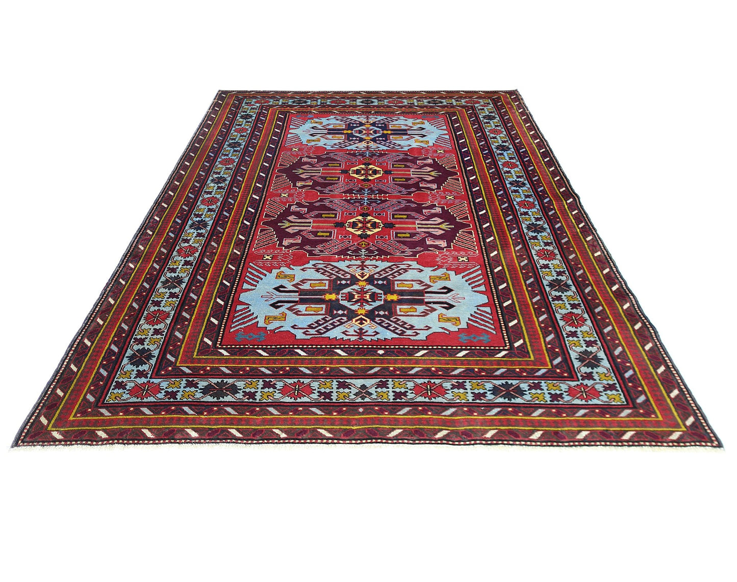 A vintage handmade Caucasian rug featuring geometric patterns in red, blue, and yellow tones.