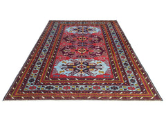 A vintage handmade Caucasian rug featuring geometric patterns in red, blue, and yellow tones.