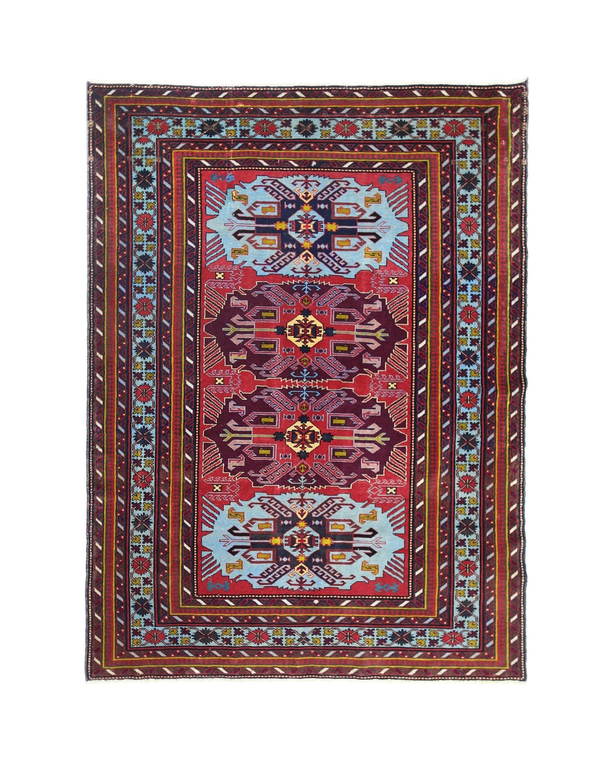A vintage handmade Caucasian rug featuring geometric motifs in red, blue, and purple tones.