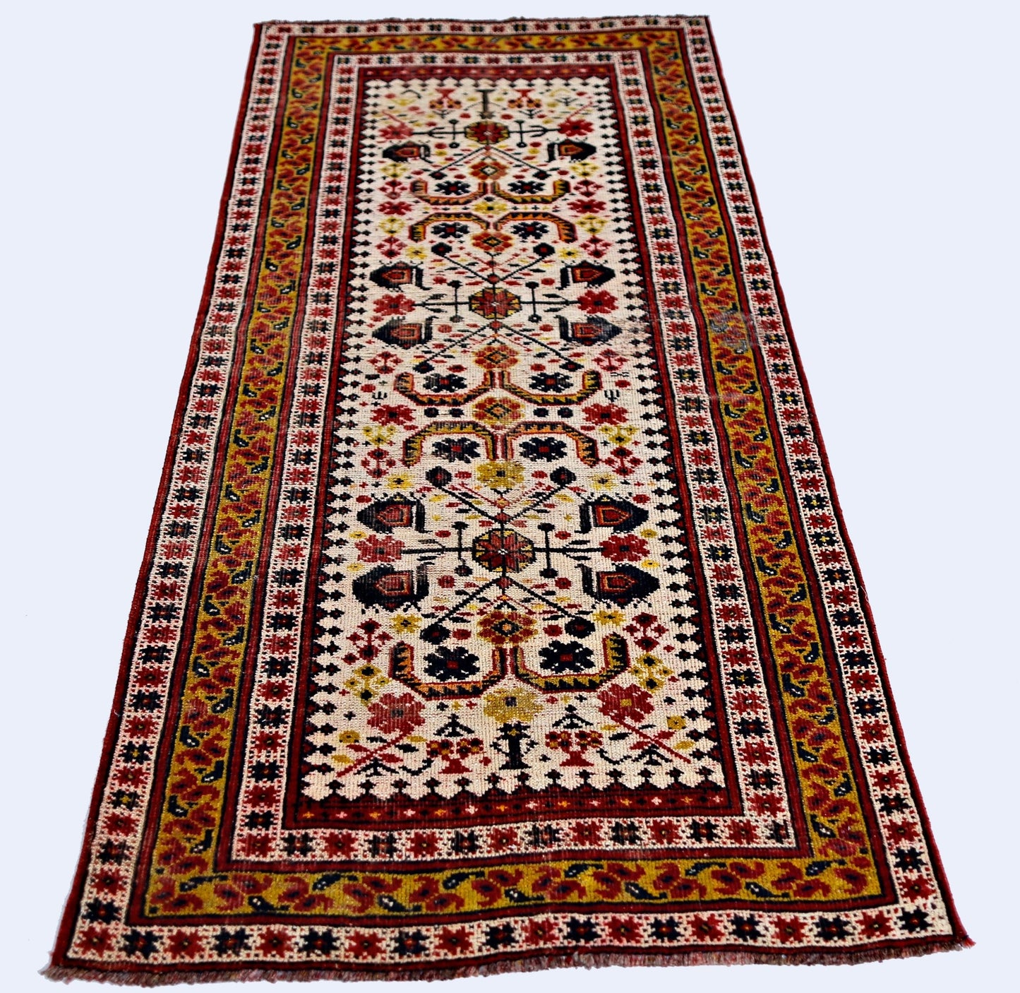 A vintage handmade Caucasian runner rug featuring a geometric floral pattern in red, yellow, and blue.