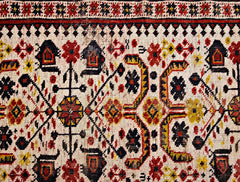 A vintage Caucasian rug featuring a geometric pattern in red, yellow, and black on a cream base.