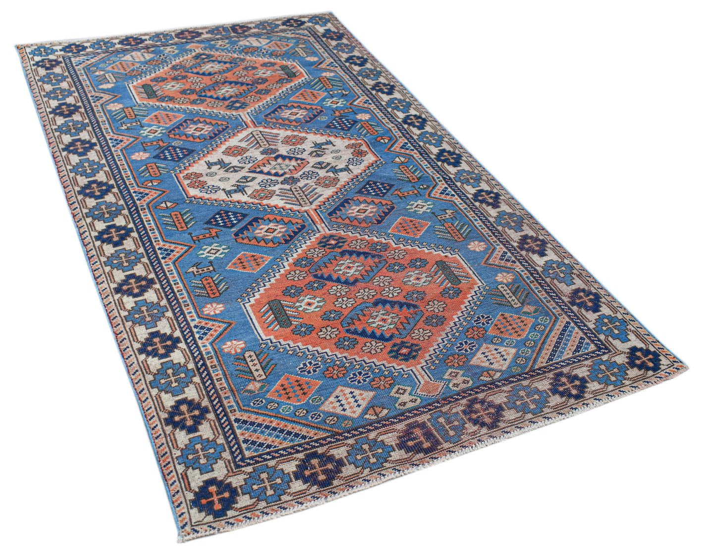 A handwoven vintage Caucasian rug featuring geometric patterns in blue, orange, and cream.