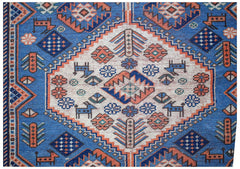 A handwoven vintage Caucasian rug featuring a blue field with geometric floral and animal motifs.