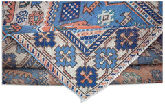 A handwoven vintage Caucasian wool rug featuring geometric patterns in blue, cream, and orange.