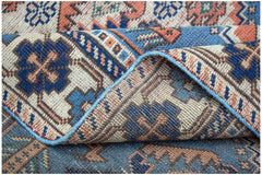 A handwoven vintage Caucasian wool rug featuring geometric patterns in blue, orange, and cream.
