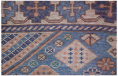 A close-up of a vintage handwoven Caucasian rug featuring geometric patterns in blue and tan.