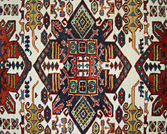 A vintage handwoven Caucasian rug featuring a geometric pattern in red, blue, and cream tones.