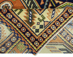 A vintage Caucasian rug featuring intricate geometric patterns in vibrant orange, blue, and cream.