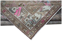 A vintage handwoven Persian rug featuring a faded geometric pattern in beige, pink, and blue.