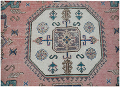 A vintage handmade Caucasian wool rug featuring a central medallion on a pink field.