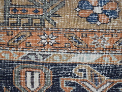 A close-up of a vintage handwoven Persian rug featuring geometric patterns in blue and orange.