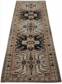 Vintage Caucasian Kazak runner with a soft peach field, bold navy geometric medallions, and intricate hooked borders.