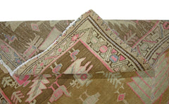 A vintage Caucasian runner rug with a brown background and traditional geometric patterns.