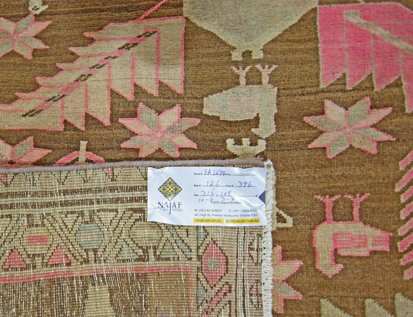 A vintage Caucasian runner featuring a traditional geometric pattern in brown, pink, and beige.