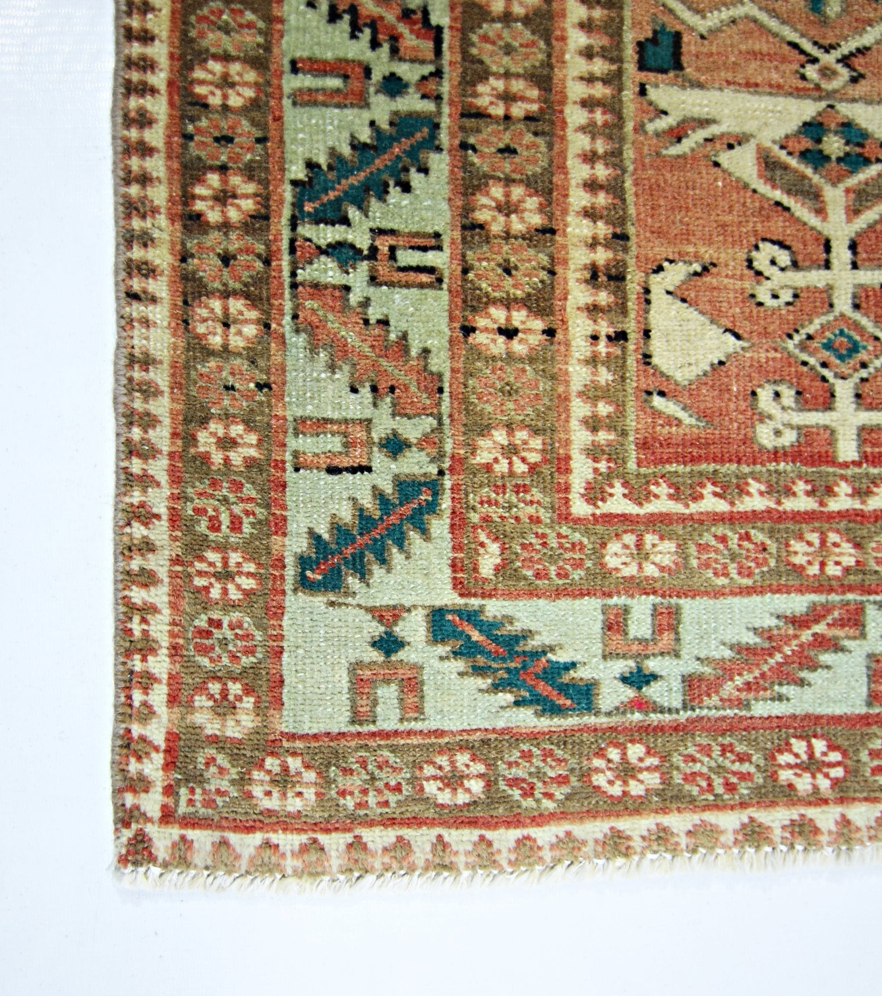 A corner view of a handmade vintage Persian rug featuring intricate floral and geometric patterns.