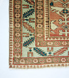 A corner view of a handmade vintage Persian rug featuring intricate floral and geometric patterns.