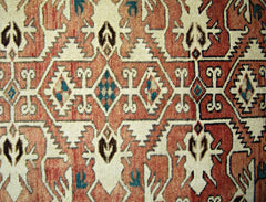 A vintage Persian rug featuring a geometric pattern in shades of red, cream, and teal.