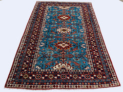A vintage handmade Caucasian Shirvan rug featuring a blue field with geometric floral motifs.