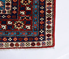 A vintage Caucasian Shirvan rug featuring intricate geometric patterns in red, blue, and cream.