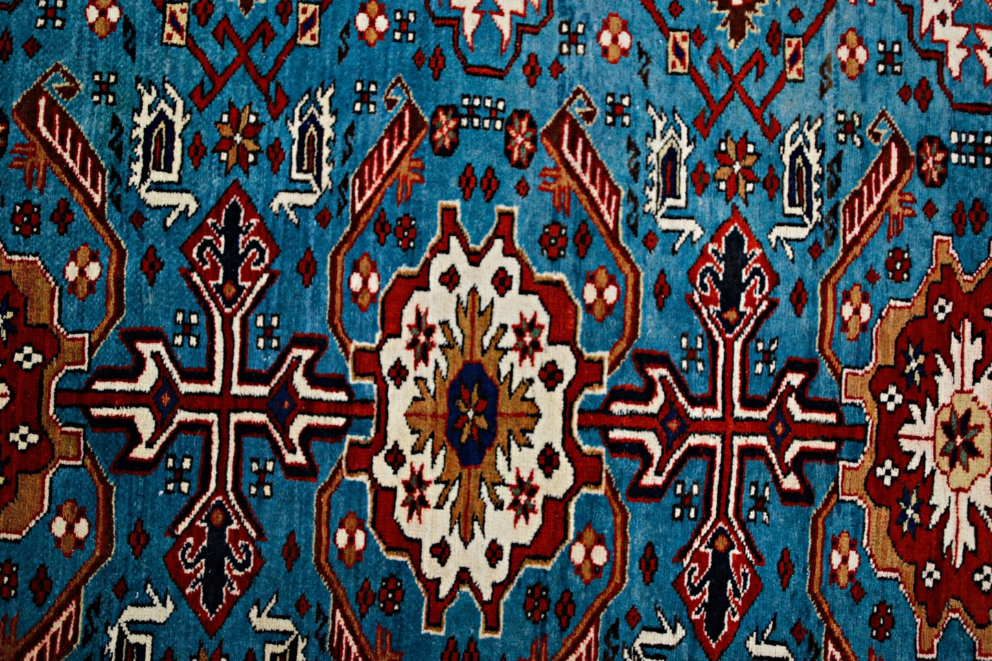 A vintage Caucasian Shirvan rug featuring intricate geometric patterns in blue, red, and white.