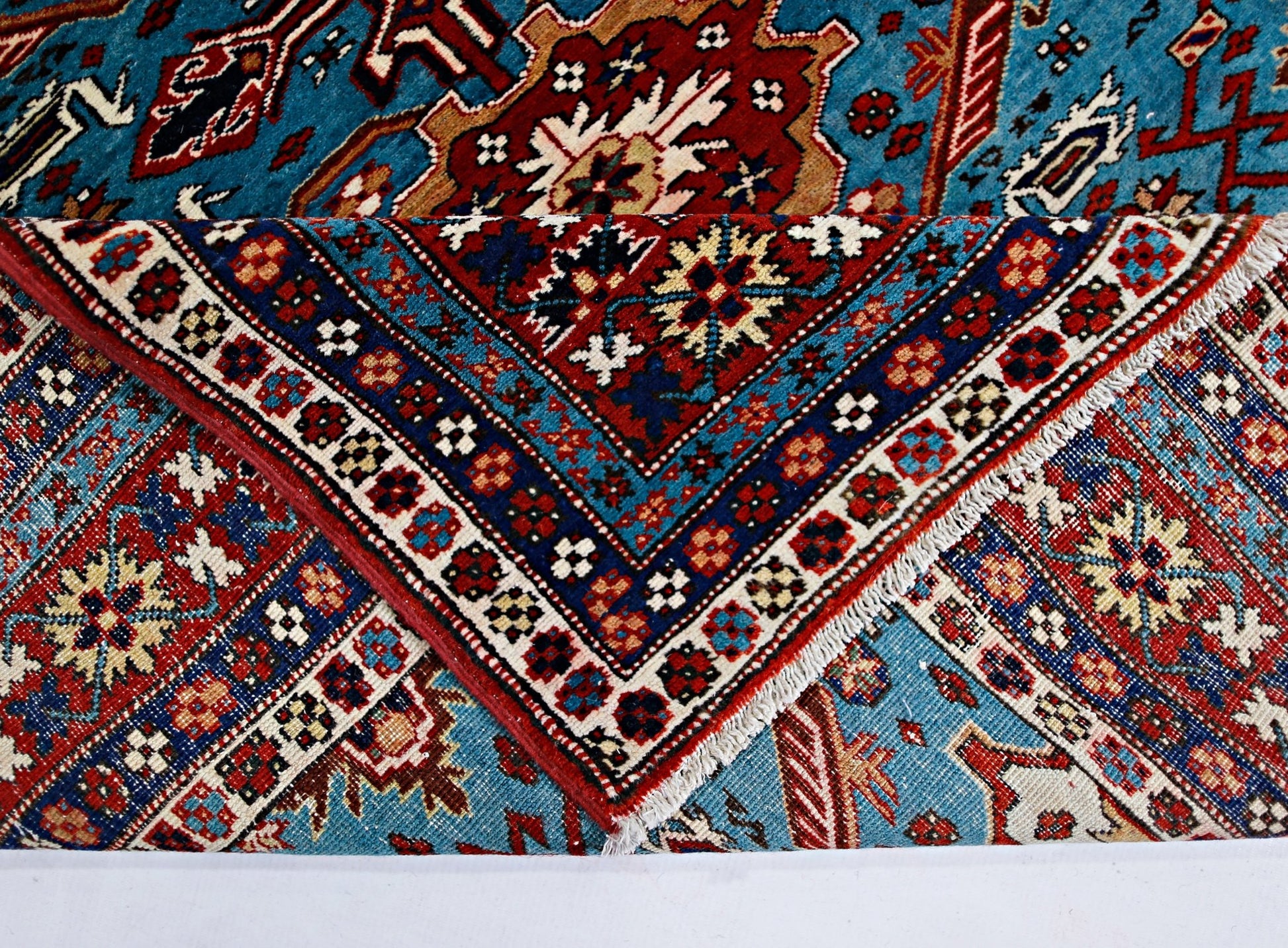 A vintage Caucasian Shirvan rug with intricate geometric patterns in blue, red, and cream.