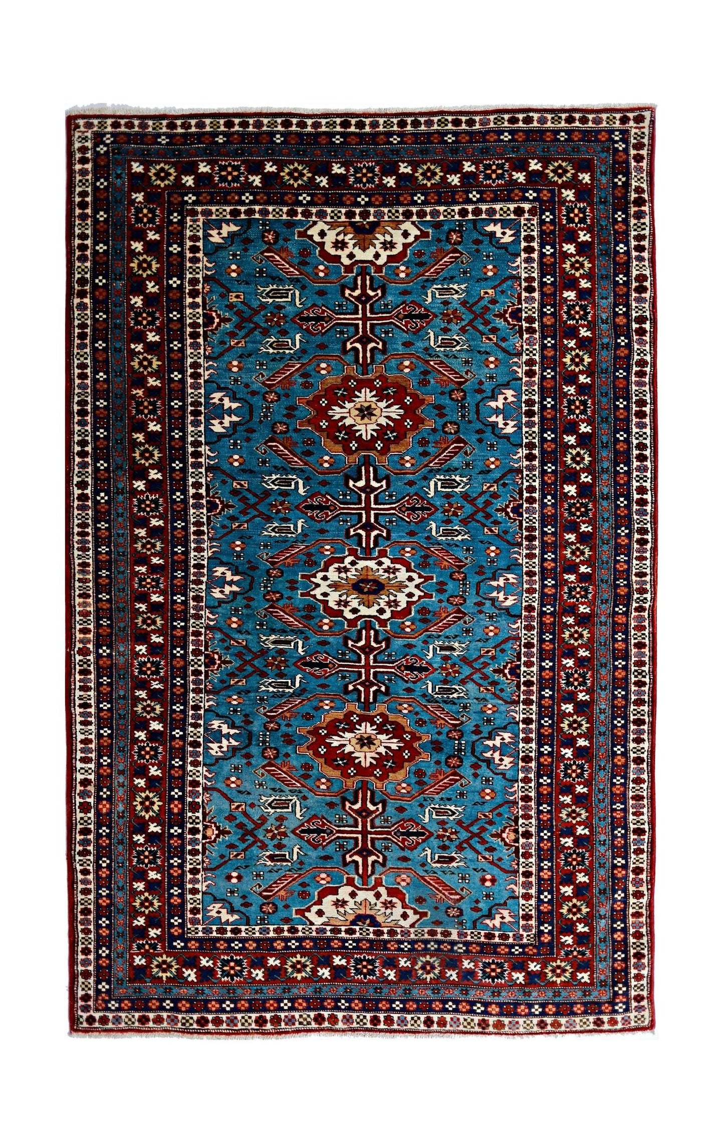 A vintage handmade Caucasian Shirvan rug featuring geometric patterns in blue, red, and cream.