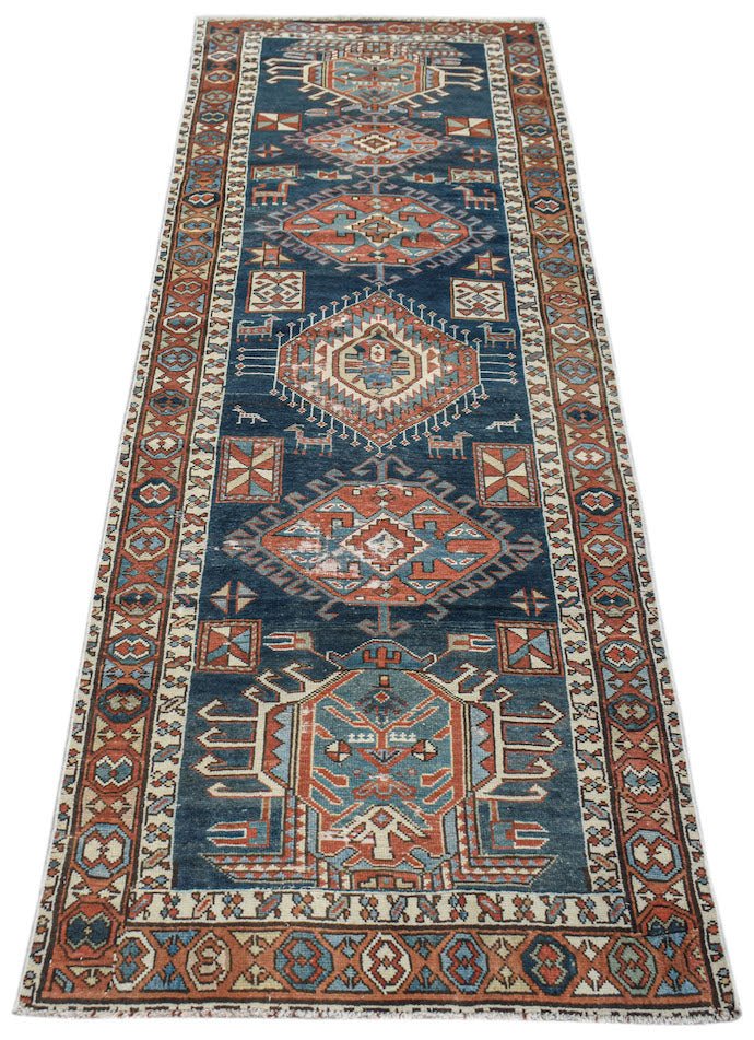 A vintage handwoven Caucasian Shirvan runner featuring geometric patterns in blue and red wool.