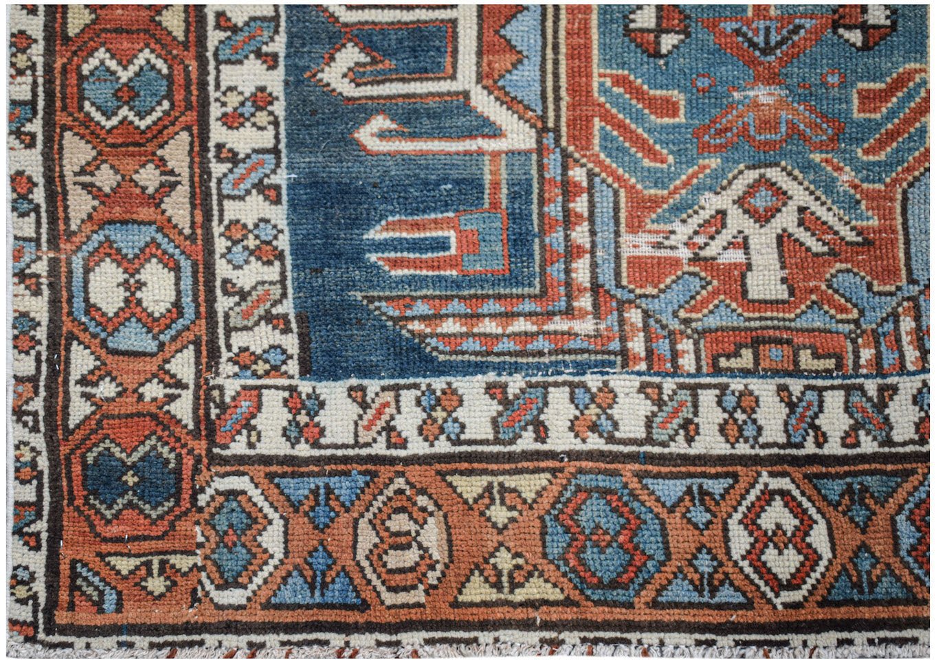 A handwoven vintage Caucasian Shirvan runner featuring geometric patterns in blue, red, and cream.