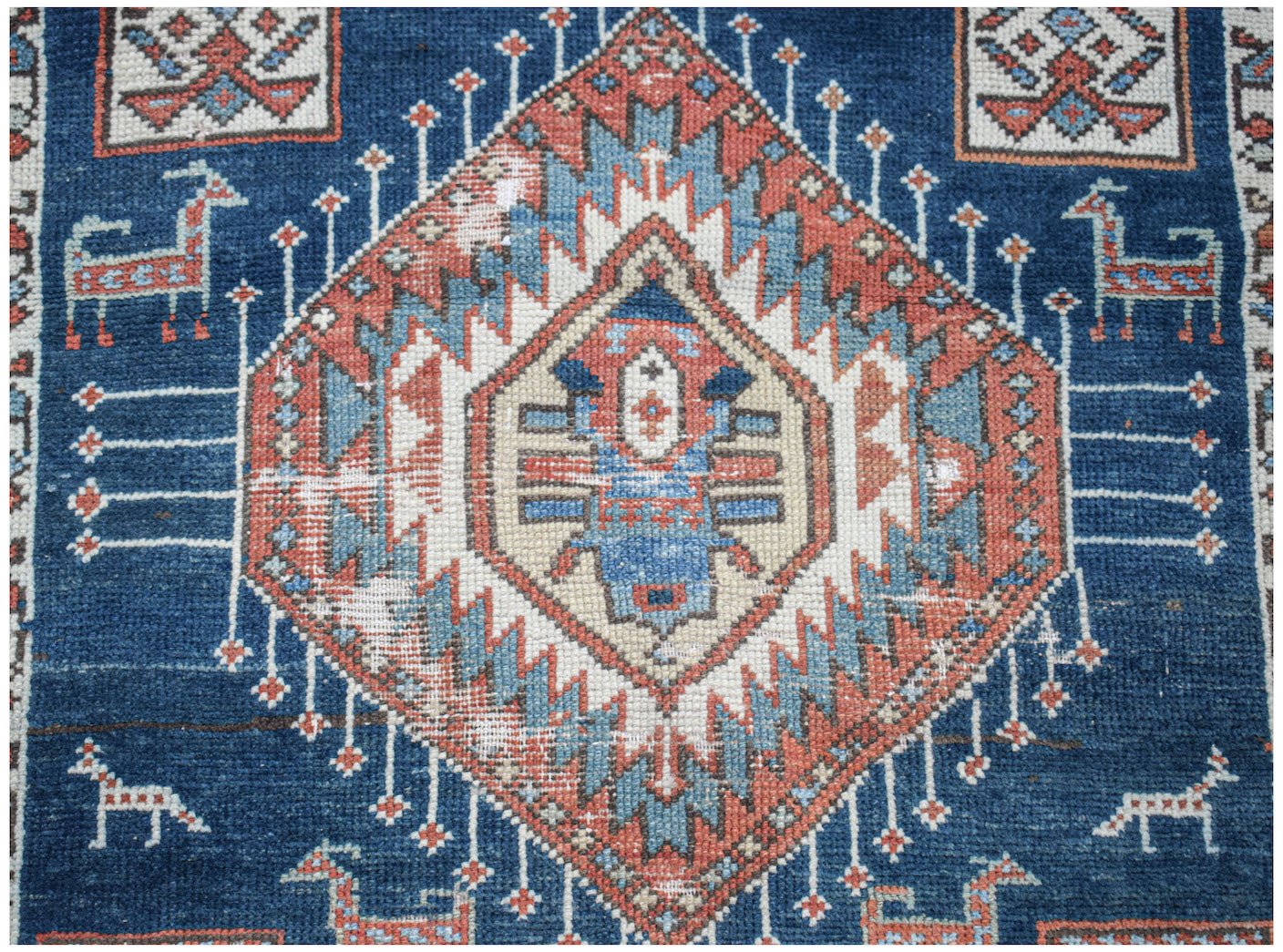 A vintage handwoven Caucasian Shirvan runner featuring a central diamond motif and animal figures.