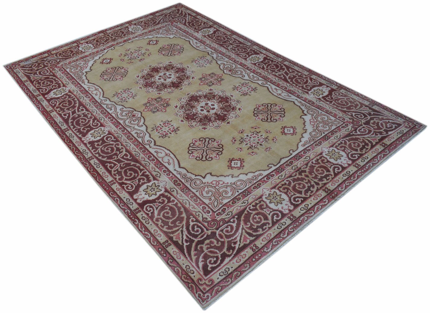 A vintage handwoven Chinese Khotan rug featuring a floral medallion pattern in red and beige.
