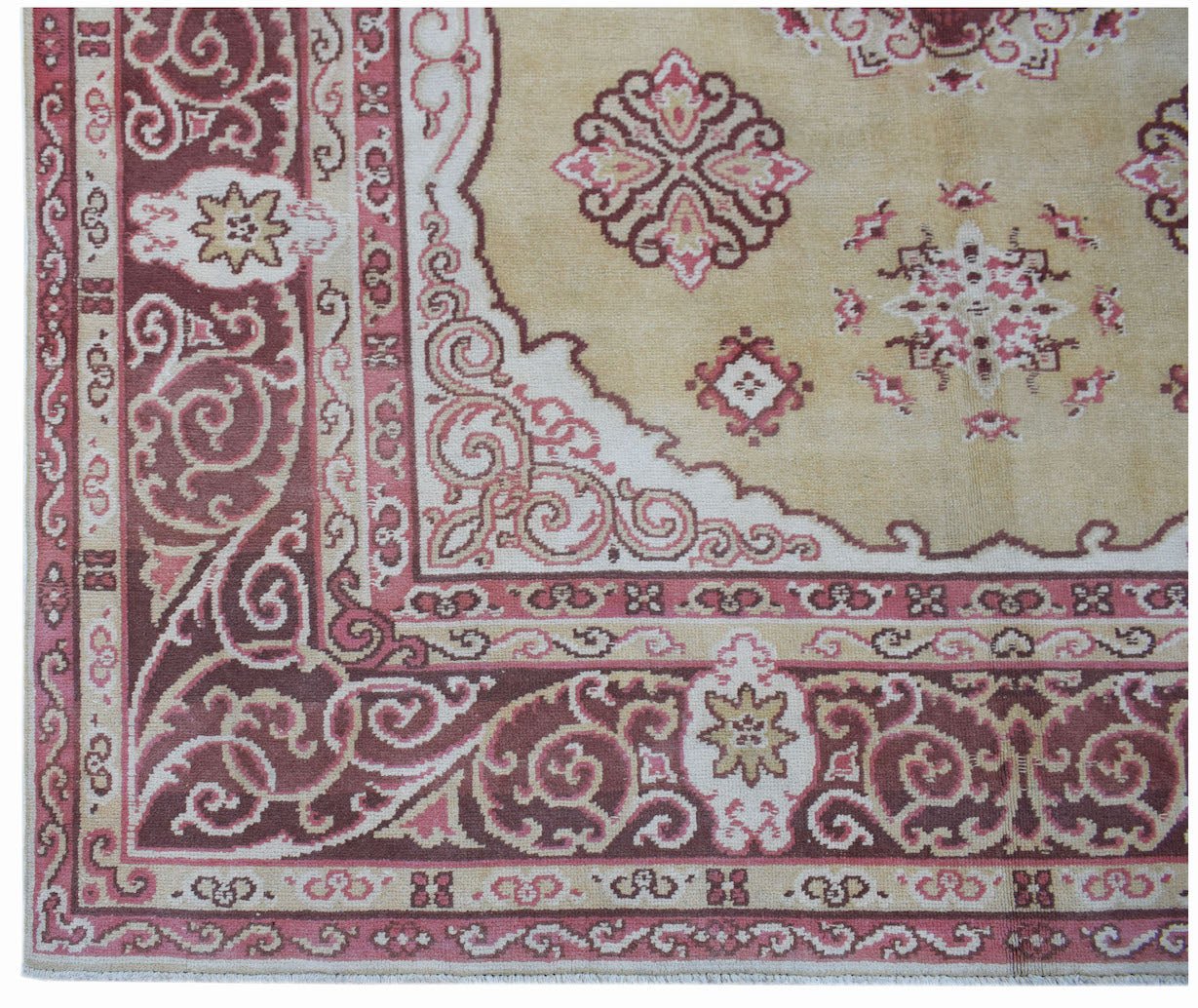 A vintage Chinese Khotan rug featuring a beige field with pink and maroon floral motifs.