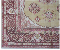 A vintage Chinese Khotan rug featuring a beige field with pink and maroon floral motifs.