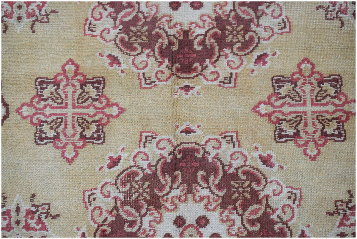 A vintage Chinese Khotan rug featuring a repeating geometric floral pattern in red and beige.