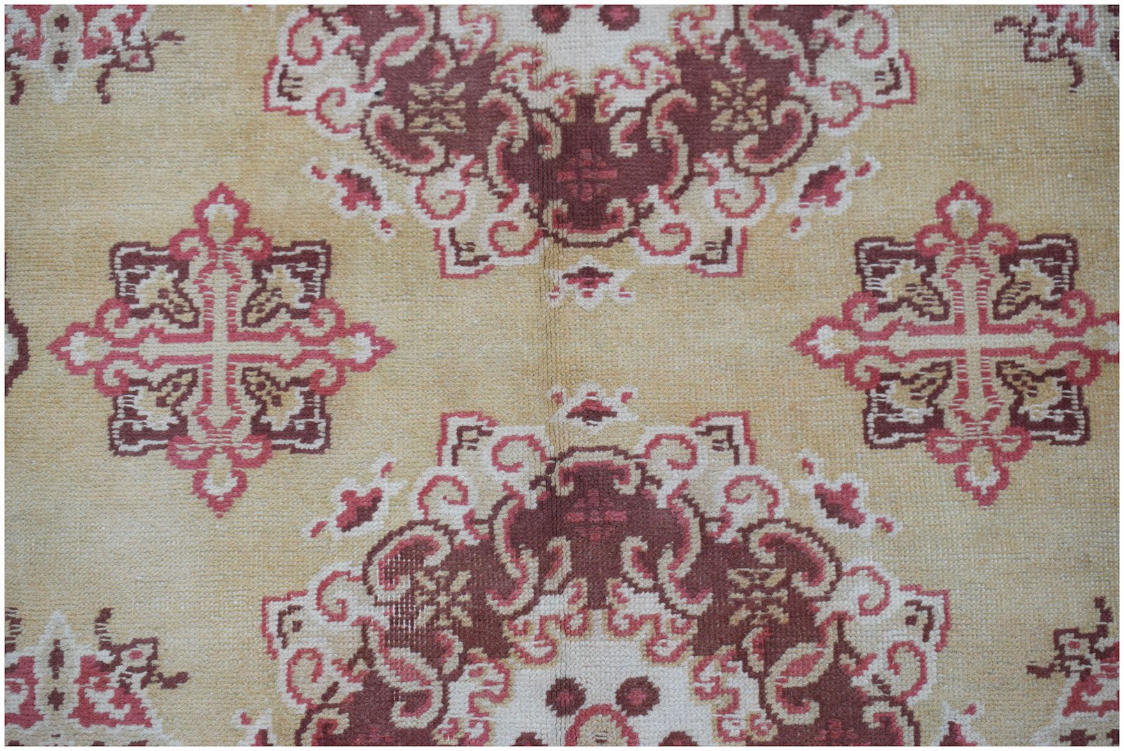 A vintage Chinese Khotan rug featuring a repeating geometric floral pattern in red and beige.