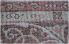 A close-up of a vintage Chinese Khotan rug featuring intricate floral patterns in pink and brown.
