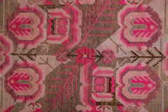 A vintage handwoven Khotan rug featuring an intricate pomegranate pattern in vibrant pink and brown.