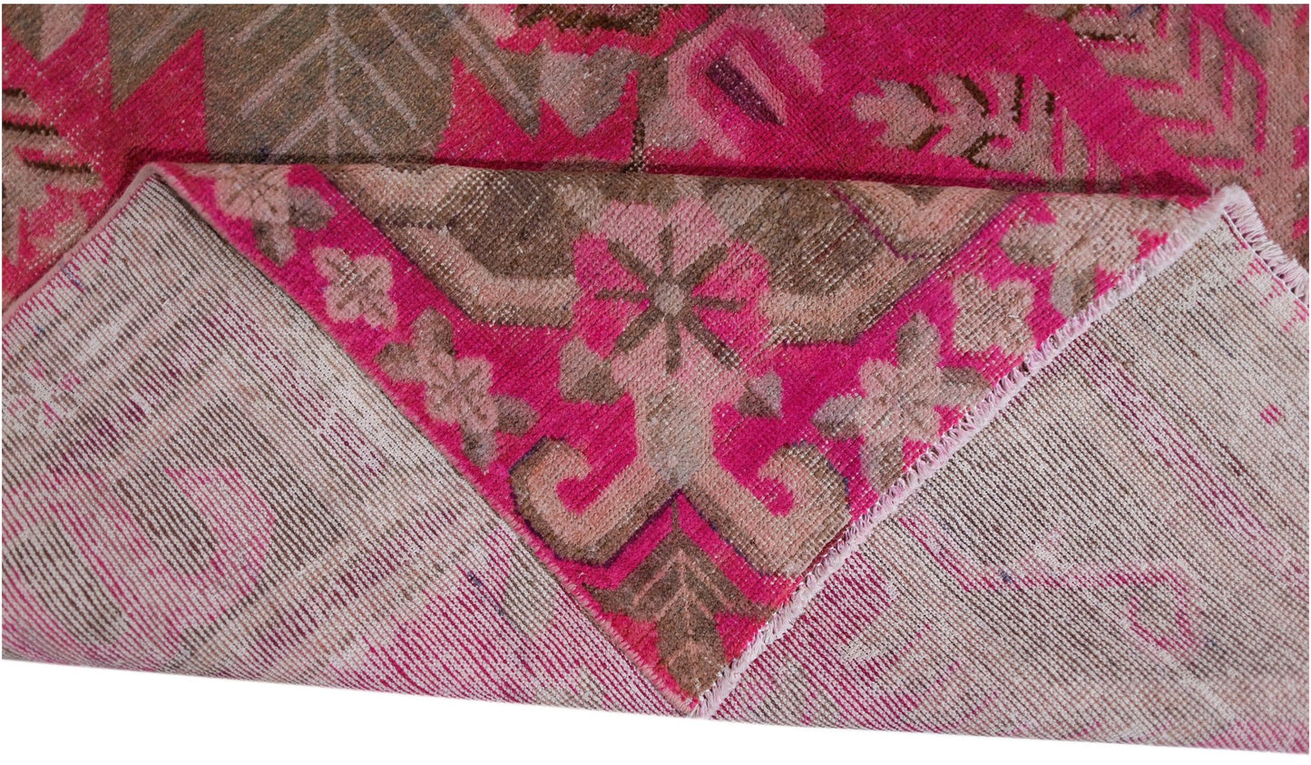 A vintage handwoven Khotan rug featuring an intricate pomegranate pattern in vibrant pink and brown.