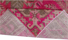 A vintage handwoven Khotan rug featuring an intricate pomegranate pattern in vibrant pink and brown.