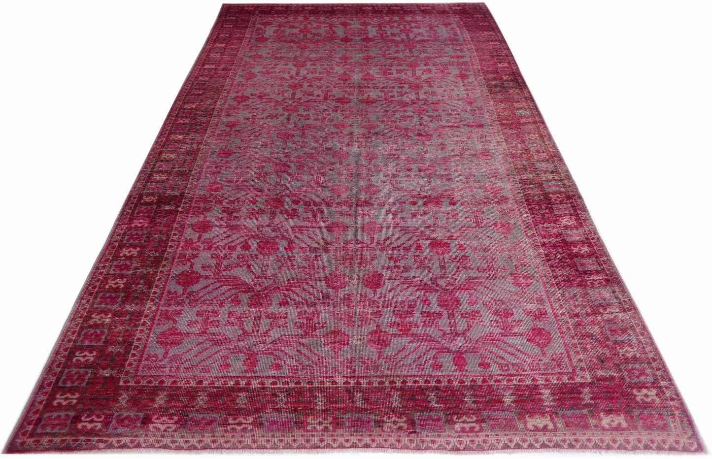 An antique handwoven Khotan rug featuring an intricate pomegranate pattern in vibrant pink.